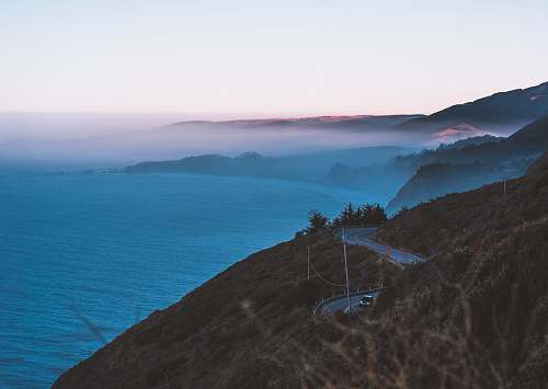 nature body of water and road hills surrounded by fogs big sur